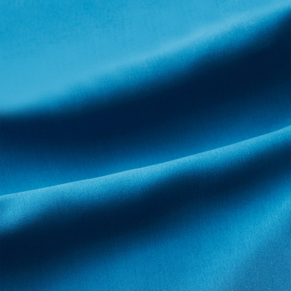 The Turnbull & Asser Blue Silk Hyde Pyjama Set features a modern fit with a long-sleeve button-up top, three pockets, white trim, and elastic-waist pants, all shown on a white background.