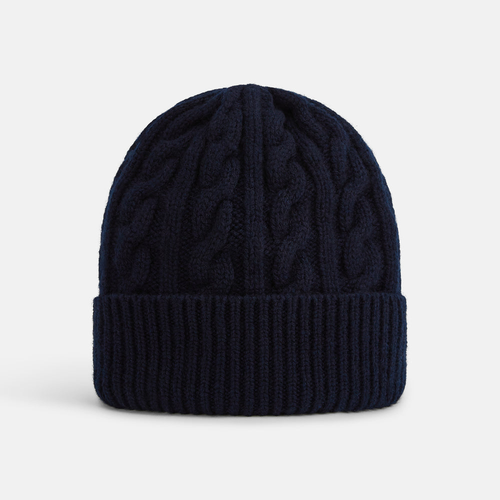 The Turnbull & Asser Midnight Blue Cable Knit Cashmere Beanie features a ribbed folded brim and chunky cable pattern, expertly knitted in England, and shown against a plain white background.