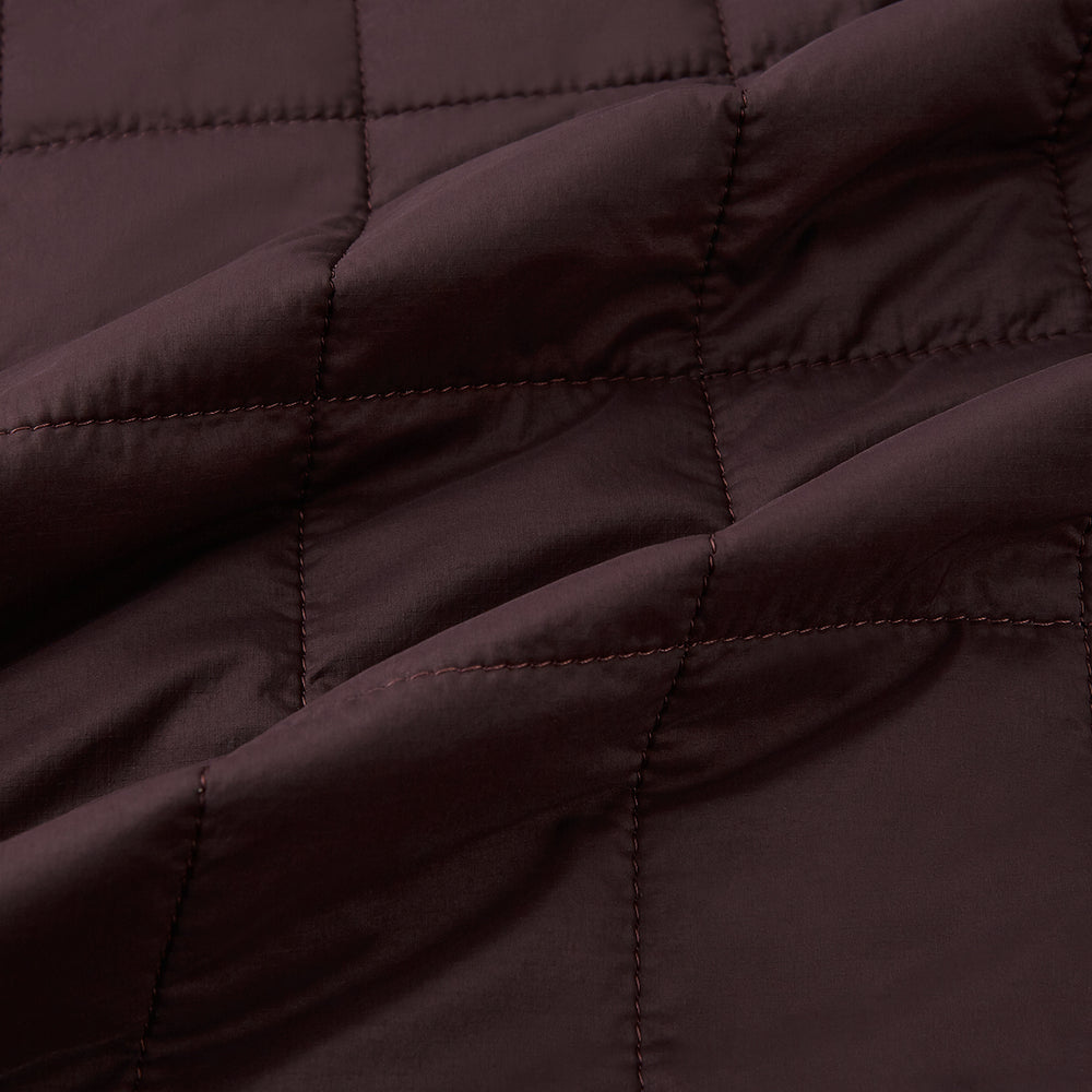The Turnbull & Asser Burgundy Quilted Gilet is a sleeveless, lightweight layer featuring a front zipper, slanted chest pocket, adjustable side tabs, and two zippered side pockets, shown on a plain white background.
