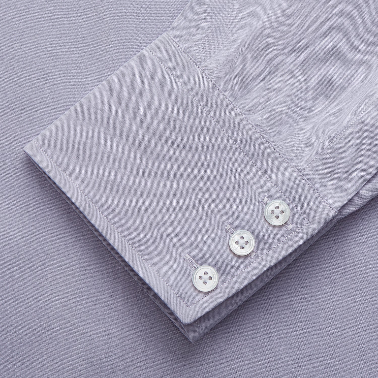 View 3 of product The Turnbull & Asser Lilac Silk Regular Fit Flaxton Shirt features long sleeves, a classic collar, white buttons, and a curved hem, shown laid flat on a white background.