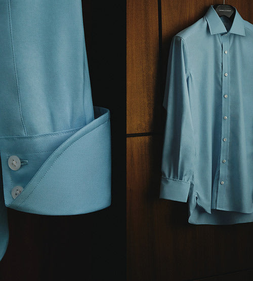 A light blue dress shirt with white buttons is shown in two views: a close-up of the cuff with button details and a full view of the shirt hanging on a wooden wardrobe.
