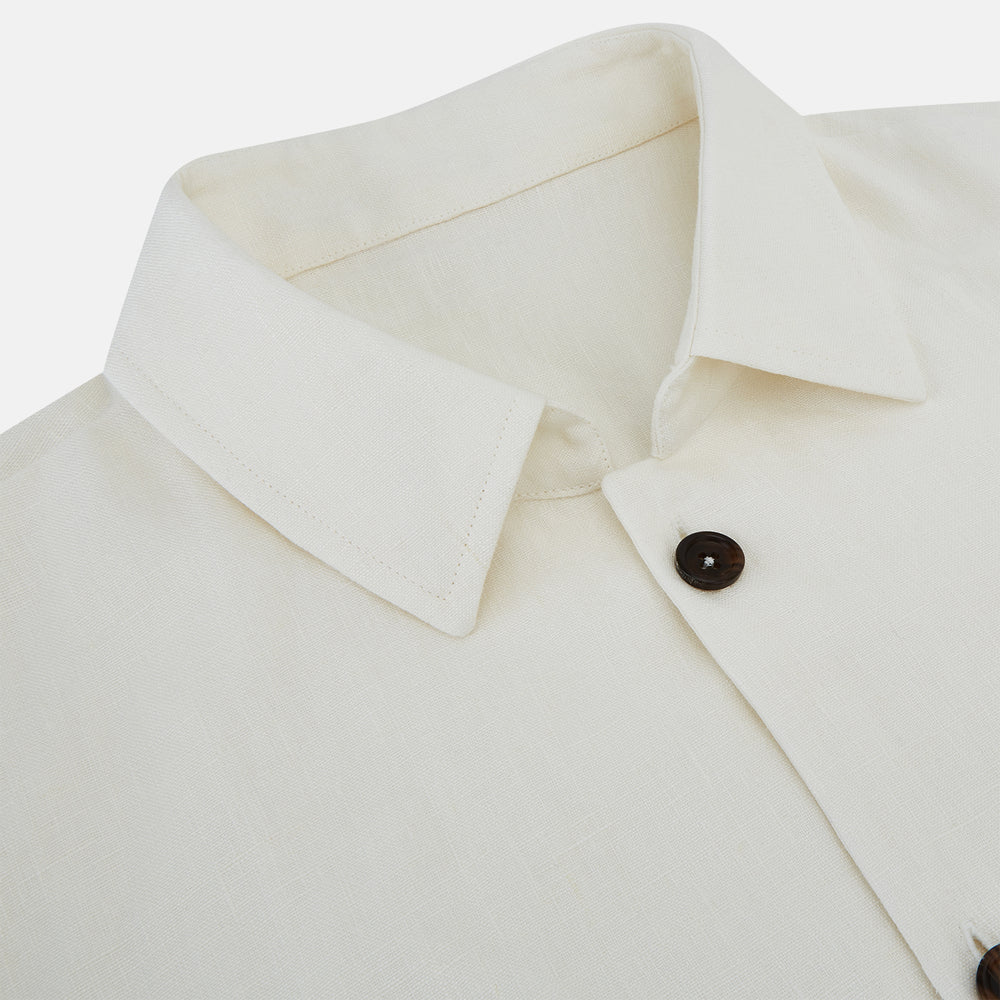 The Vanilla Linen Holland Shacket by Turnbull & Asser, a white Irish linen button-up with a collar, brown buttons, and four pockets, is laid flat on a white background—perfect as lightweight outerwear.