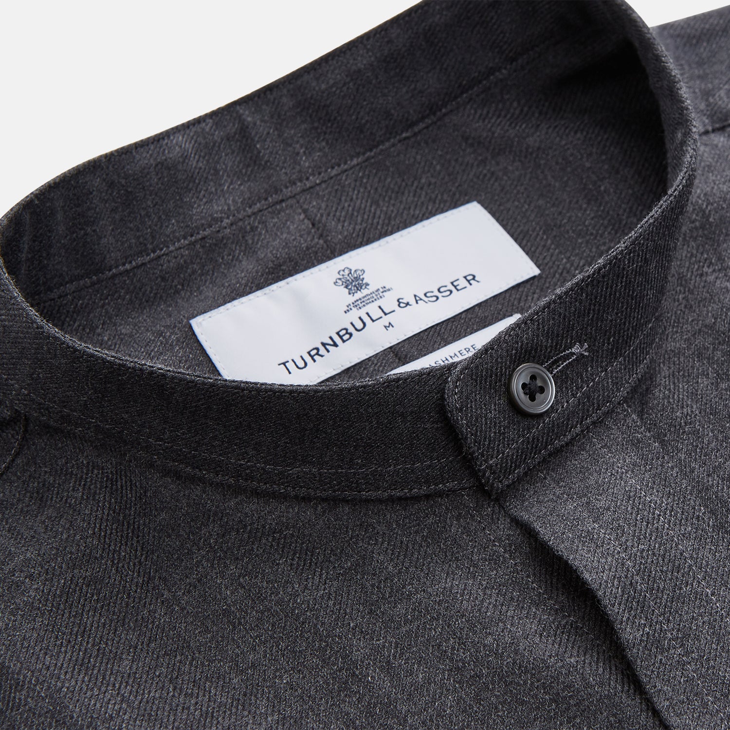 View 2 of product The Turnbull & Asser Charcoal Cotton Blend Weekend Fit Blake Shirt is a long-sleeve, stand-collar shirt with white buttons. Its minimalist design, with no pockets or patterns, makes it perfect for casual wear. Displayed flat on a white background.