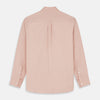 View 8 of product A man faces forward in a relaxed pose against a beige background, wearing the Turnbull & Asser Pink Piece Dyed Weekend Fit Suffolk Shirt with a button-down collar, dark cuffed jeans, and black shoes.