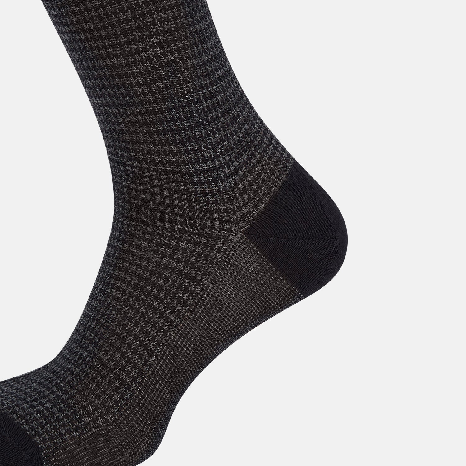 View 4 of product The Turnbull & Asser Charcoal Melange Houndstooth Long Sock is knee-high, with a subtle dark houndstooth pattern and solid black toe, heel, and cuff, shown on a white background.