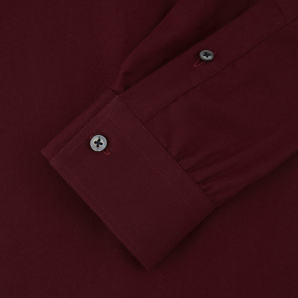 The Turnbull & Asser Burgundy Cashmerello Button Down Shirt features long sleeves, buttoned chest pockets, a spread collar, and is crafted from a soft cotton-cashmere blend, neatly displayed on a plain white background.