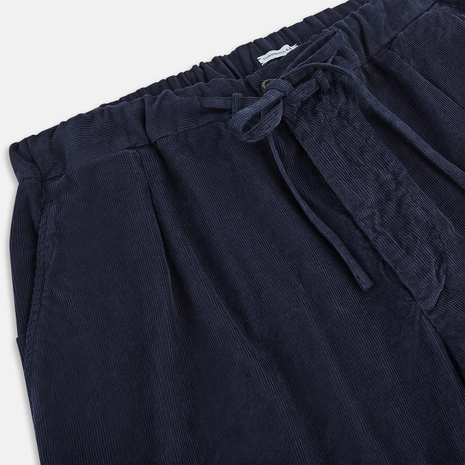 View 2 of product Turnbull & Asser's Light Navy Corduroy Miles Trousers feature a straight-leg stretch fit, elasticated waist, and matching fabric drawstring, shown on a plain white background.
