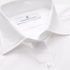 View 8 of product A woman with straight brown hair pulled back wears the Turnbull & Asser White Cotton Marlene Shirt, featuring classic menswear details, paired with high-waisted cream trousers against a neutral background.
