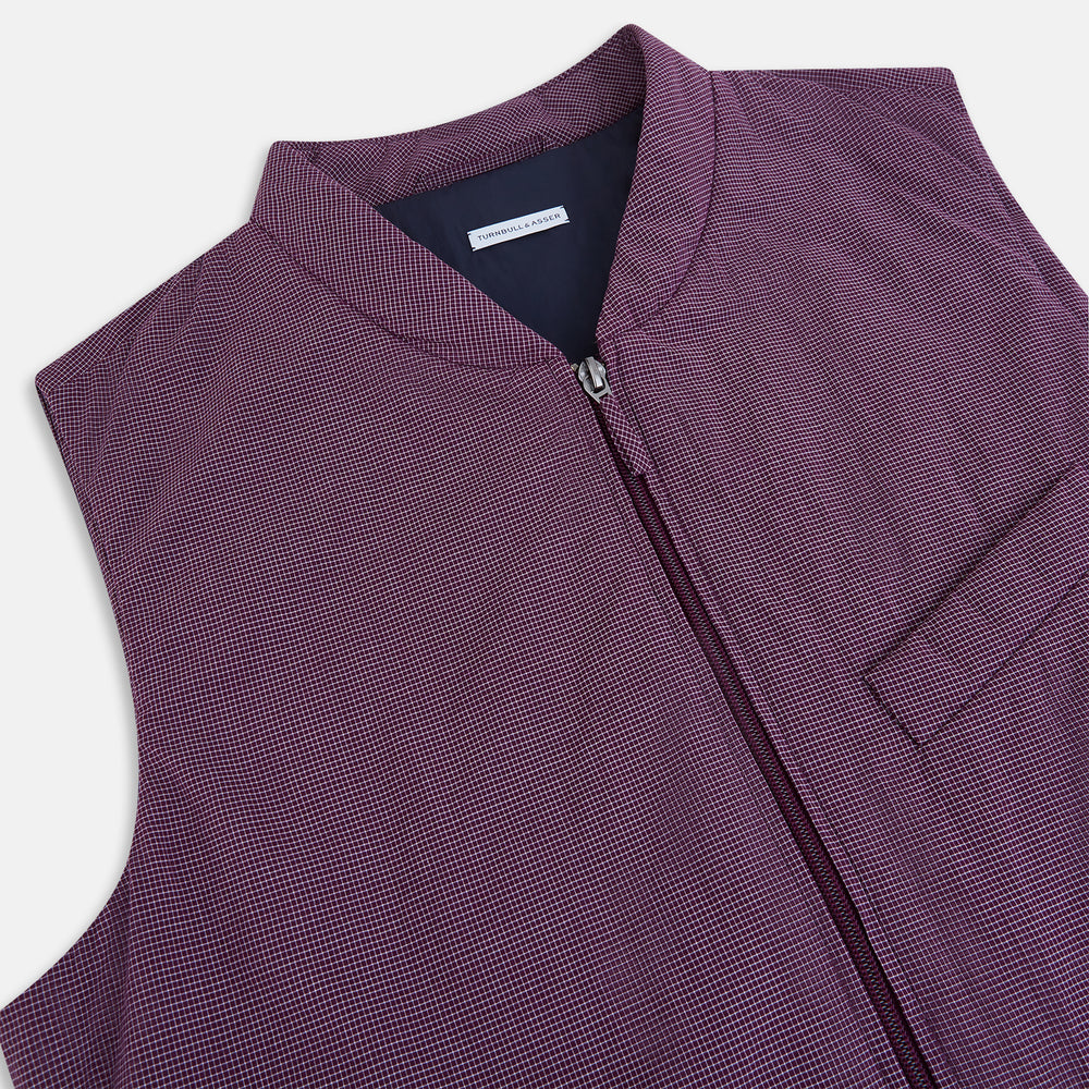 The Turnbull & Asser Burgundy Pin Check Padded Gilet features a front zipper, two zippered side pockets, a chest pocket, and a rounded hem—an ideal men’s layering piece shown on a white background.