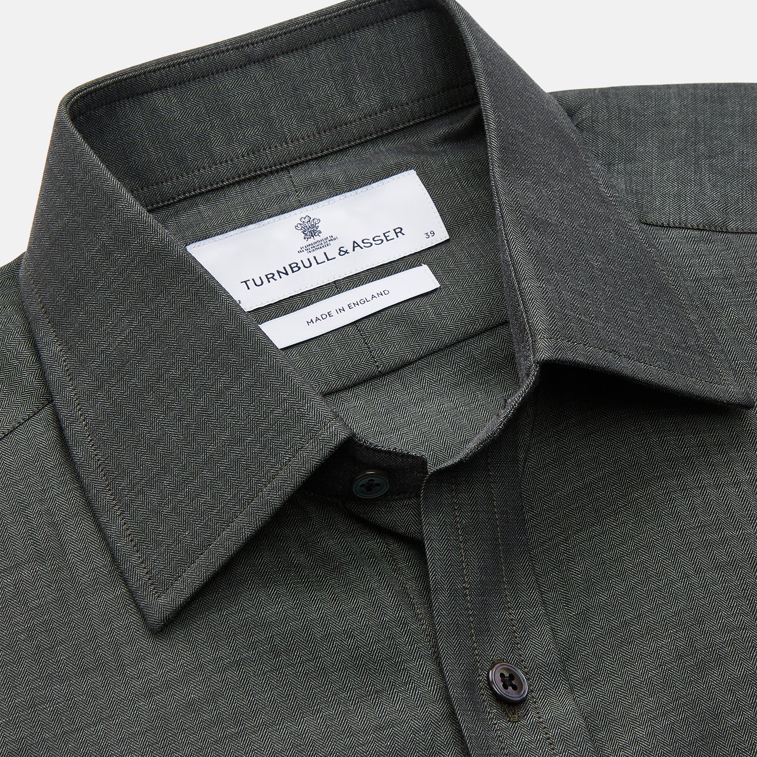 View 2 of product The Turnbull & Asser Dark Green Cotton Melange Regular Fit Mayfair Shirt features long sleeves, a T&A collar, buttoned cuffs, and a slightly rounded hem, shown laid flat on a white background.
