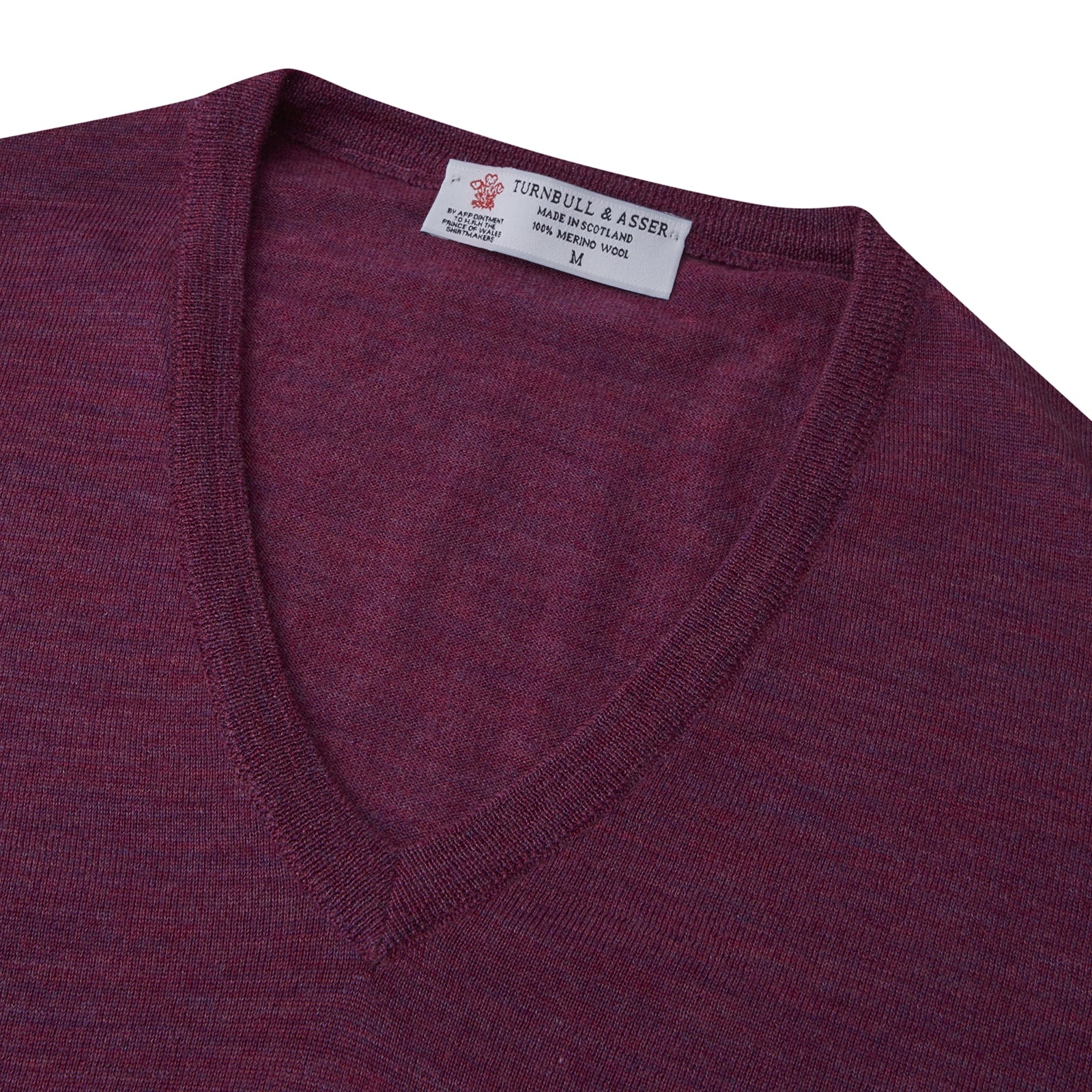 View 3 of product The Turnbull & Asser Plum Fine Merino V-Neck Jumper is a lightweight, long-sleeved layer in deep burgundy, featuring ribbed cuffs and hem for a refined finish, displayed against a white background.