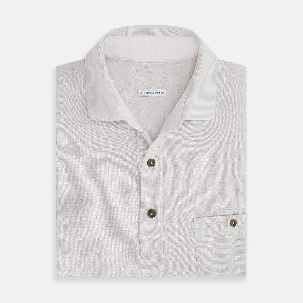 The Turnbull & Asser Pale Pink Polo Shirt is a cotton jersey short-sleeve polo with a collar, three brown buttons on the placket, and a button-flap chest pocket, shown against a white background.