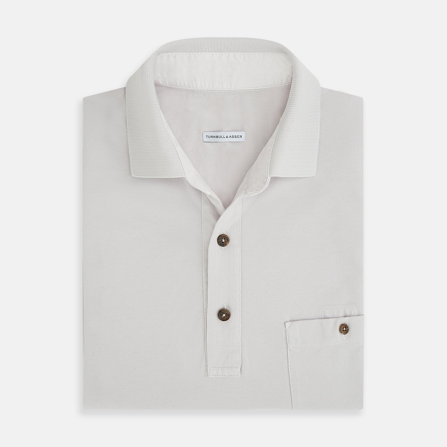 View 4 of product The Turnbull & Asser Pale Pink Polo Shirt is a cotton jersey short-sleeve polo with a collar, three brown buttons on the placket, and a button-flap chest pocket, shown against a white background.