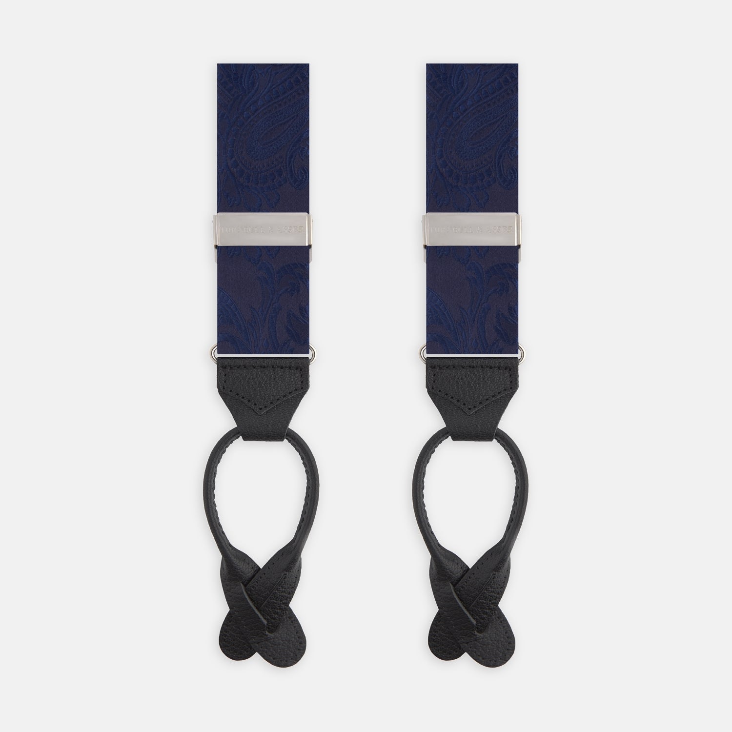 View 1 of product Turnbull & Asser’s Navy Paisley Adjustable Silk Braces feature subtle paisley patterns, silver hardware, and black leather ends with looped attachments, shown laid flat on a white background.