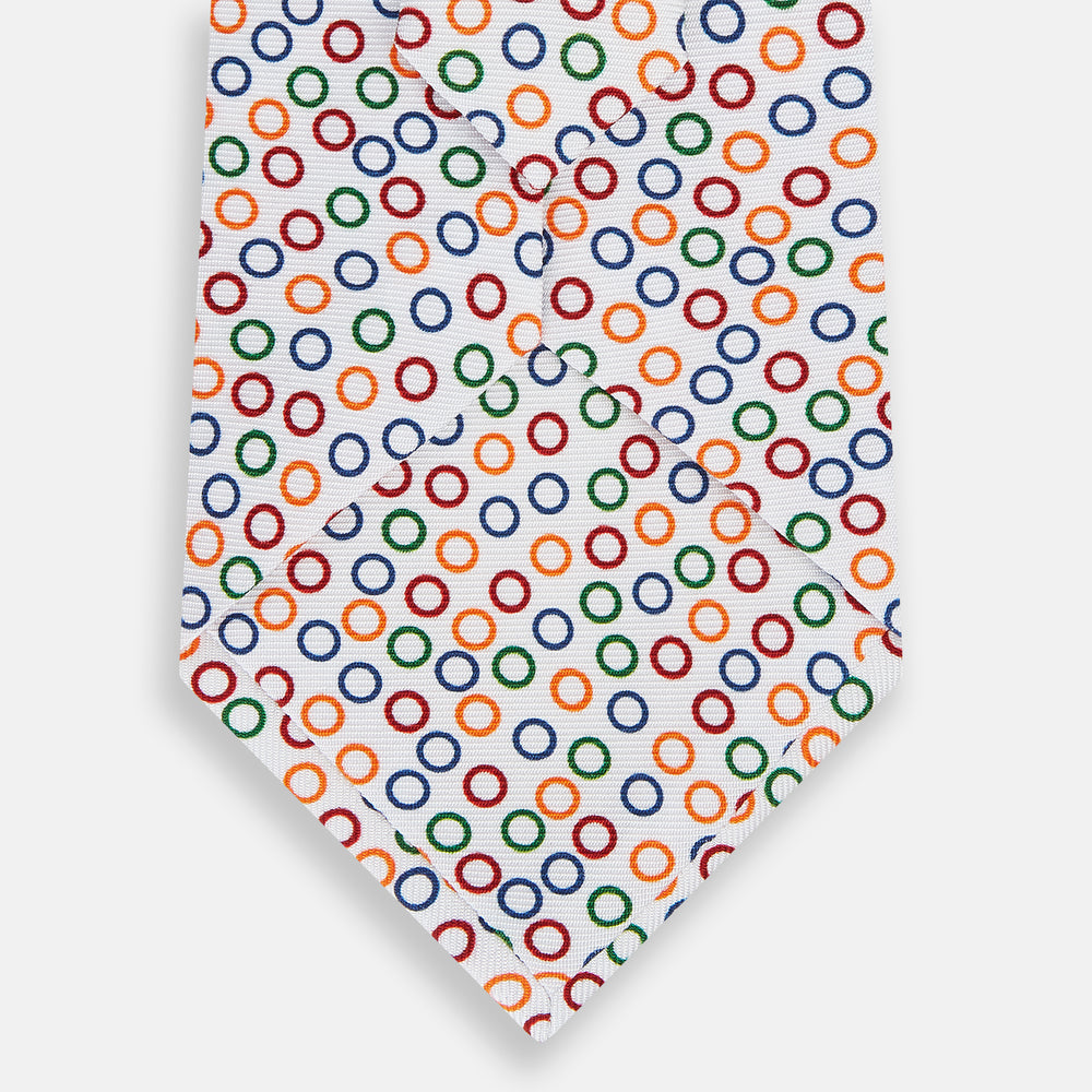 The Turnbull & Asser Confetti Circle White Silk Tie features colorful rings in red, orange, blue, and green scattered across a crisp white background.