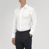 View 2 of product A neatly folded White Sea Island Quality Cotton Twill Shirt by Turnbull & Asser, featuring a T&A collar and 3-button cuffs, is displayed on a light grey background with a label visible inside the collar.