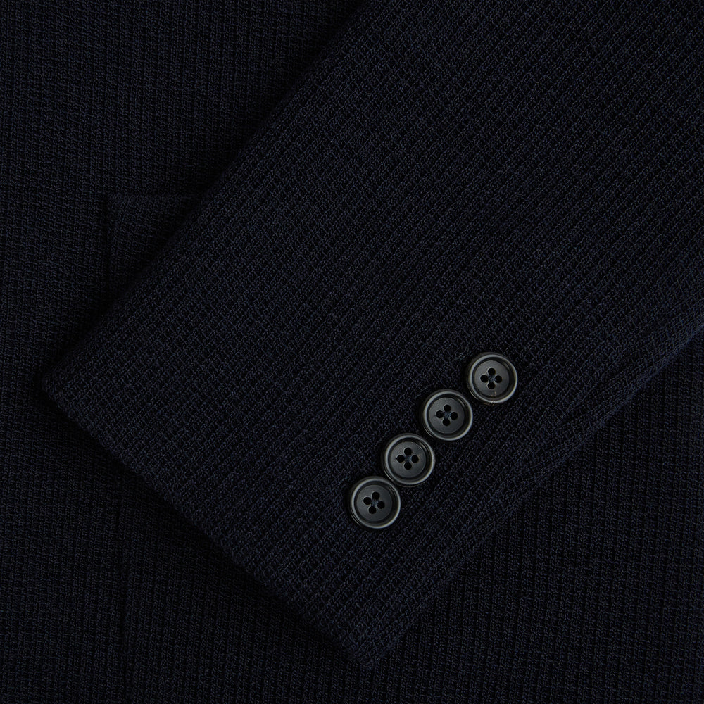 The Turnbull & Asser Navy Knitted Cambridge Blazer features a single-breasted design with three front patch pockets and two buttons, shown against a plain white background.