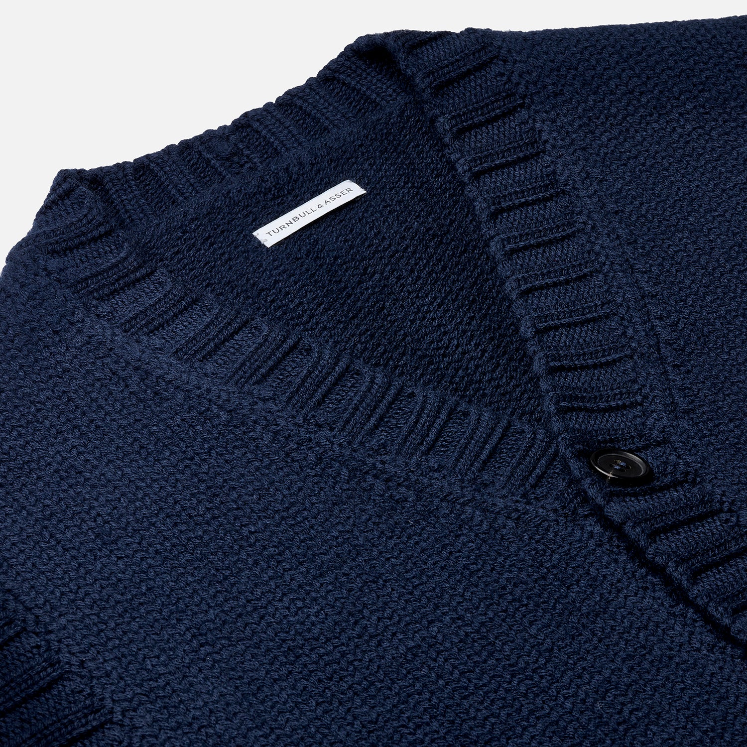 View 2 of product The NAVY MERINO V-NECK SLEEVELESS CARDIGAN by Turnbull & Asser features a button-down front, ribbed edges, and two front pockets—an elegant layering piece for stylish menswear.