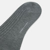 View 3 of product The Ash Long Sock by Turnbull & Asser is a single, knee-high sock in dark gray Egyptian cotton with a ribbed texture, displayed upright against a plain white background.