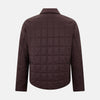 View 3 of product The Battersea Burgundy Quilted Jacket by Turnbull & Asser is a men's elegant outerwear featuring a front zipper, zippered side pockets, chest pocket, pointed collar, and buttoned cuffs, shown on a plain white background.