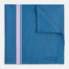 View 1 of product The Turnbull & Asser Blue and Lilac Stripe Silk Pocket Square features blue silk with white pinstripes, a bold lilac stripe near the edge, a turned-up corner revealing the reverse, and the brand name displayed in the bottom right.
