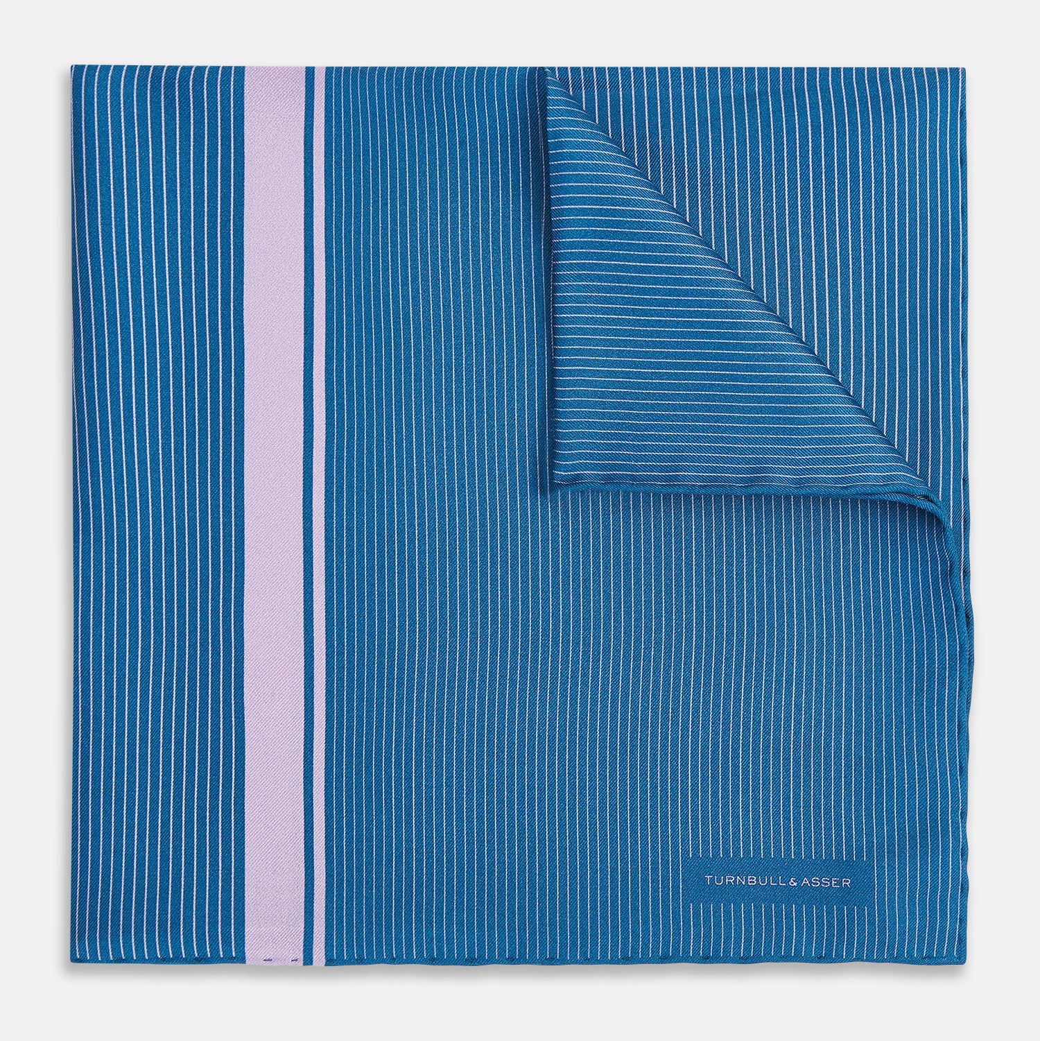 View 1 of product The Turnbull & Asser Blue and Lilac Stripe Silk Pocket Square features blue silk with white pinstripes, a bold lilac stripe near the edge, a turned-up corner revealing the reverse, and the brand name displayed in the bottom right.
