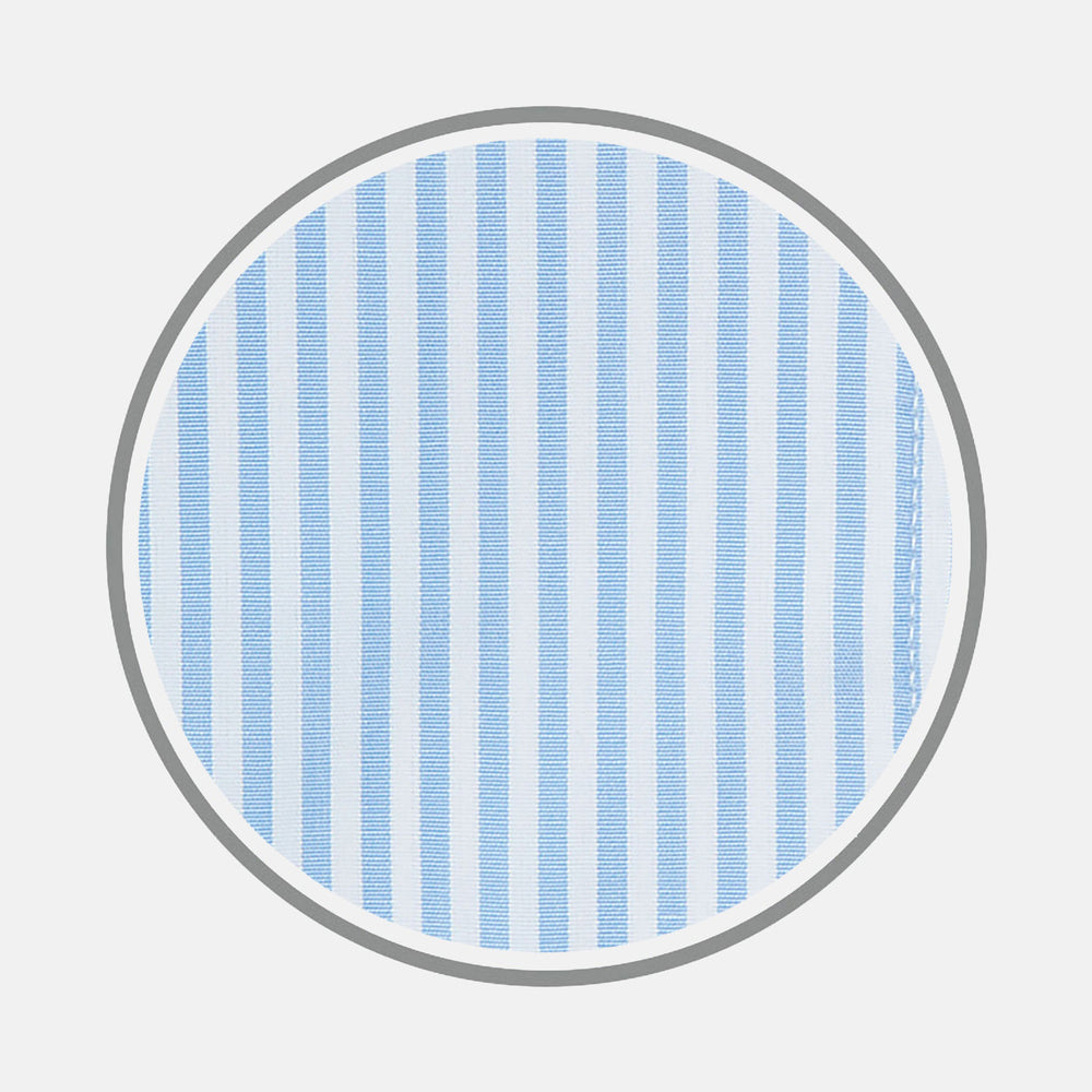 A close-up of Turnbull & Asser’s Light Blue Bengal Stripe Cotton Fabric shows its light blue and white vertical stripes pattern inside a gray circular frame on a white background.