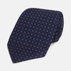 View 1 of product The Turnbull & Asser Navy and Grey Circle Silk Tie, featuring a refined pattern of evenly spaced circles, is elegantly displayed rolled up on a white background—an excellent option for modern office wear.