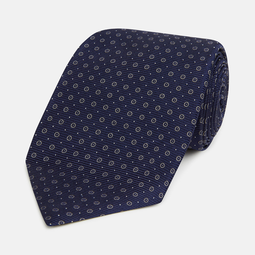 The Turnbull & Asser Navy and Grey Circle Silk Tie, featuring a refined pattern of evenly spaced circles, is elegantly displayed rolled up on a white background—an excellent option for modern office wear.