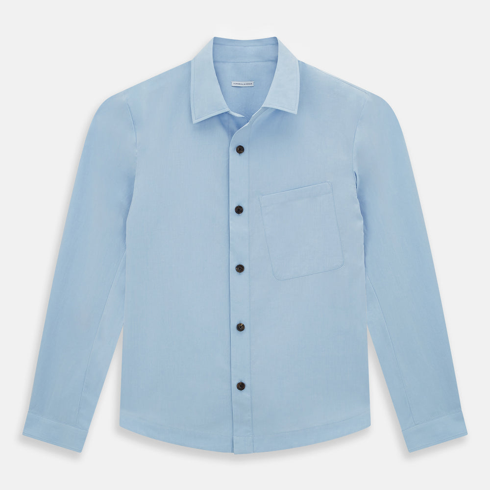 The Blue Hyde Overshirt by Turnbull & Asser features a light blue hue, long sleeves, a button-up front, and a single chest pocket. Crafted from sanforised cotton and shown laid flat on a white background.
