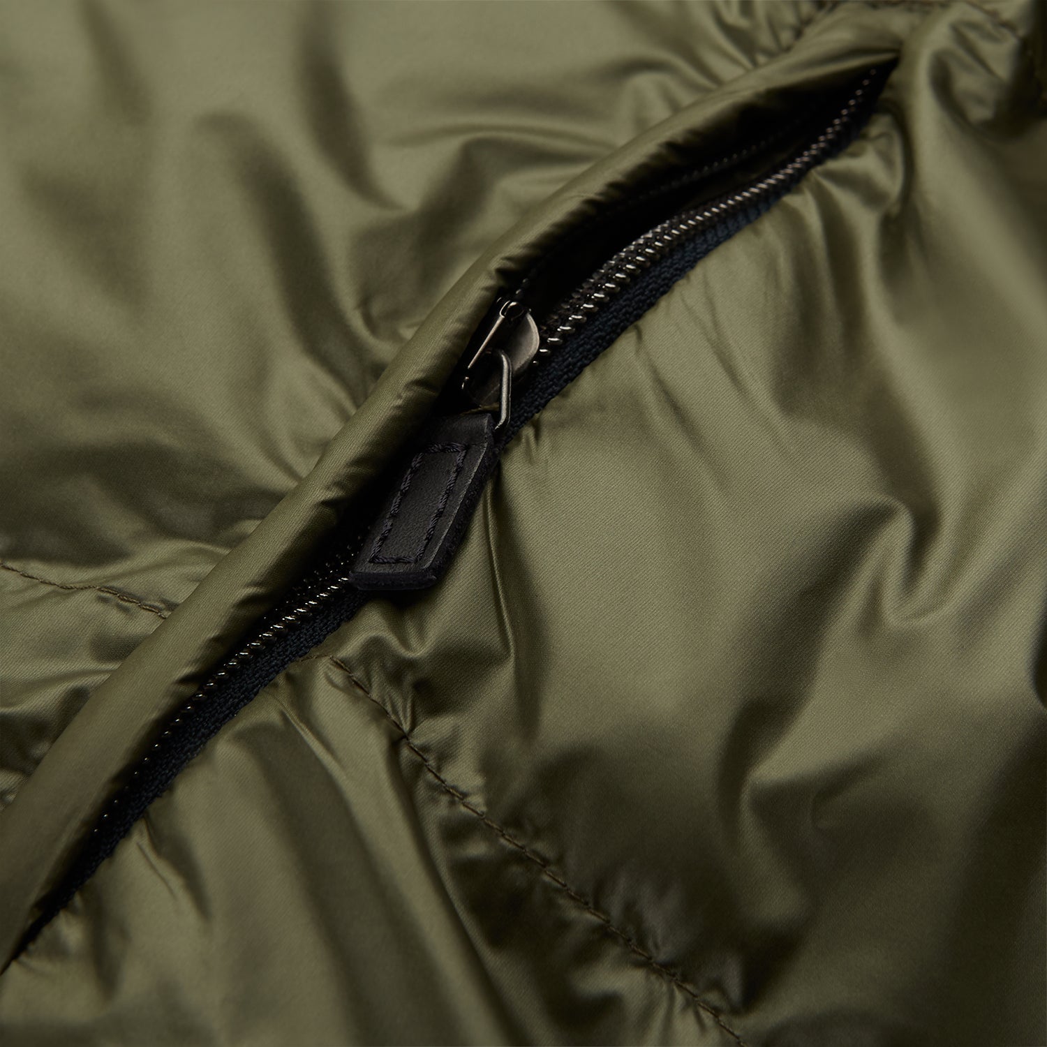 View 6 of product A man stands against a plain background wearing the Turnbull & Asser Green Peyton Sealup Quilted Gilet over a striped shirt, dark trousers, and white sneakers, with his hands in his pockets and looking slightly to the side.