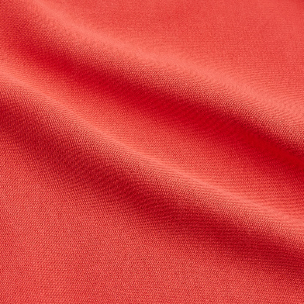 The Turnbull & Asser Women's Coral Pink Silk Thelma Pyjama Set features a long-sleeve button-up top with two front pockets and matching drawstring pants, shown on a white background.