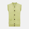 View 1 of product The Melon Green Sleeveless Cardigan by Turnbull & Asser features a ribbed collar, large brown buttons, and two front pockets—a stylish layering piece shown against a plain white background.
