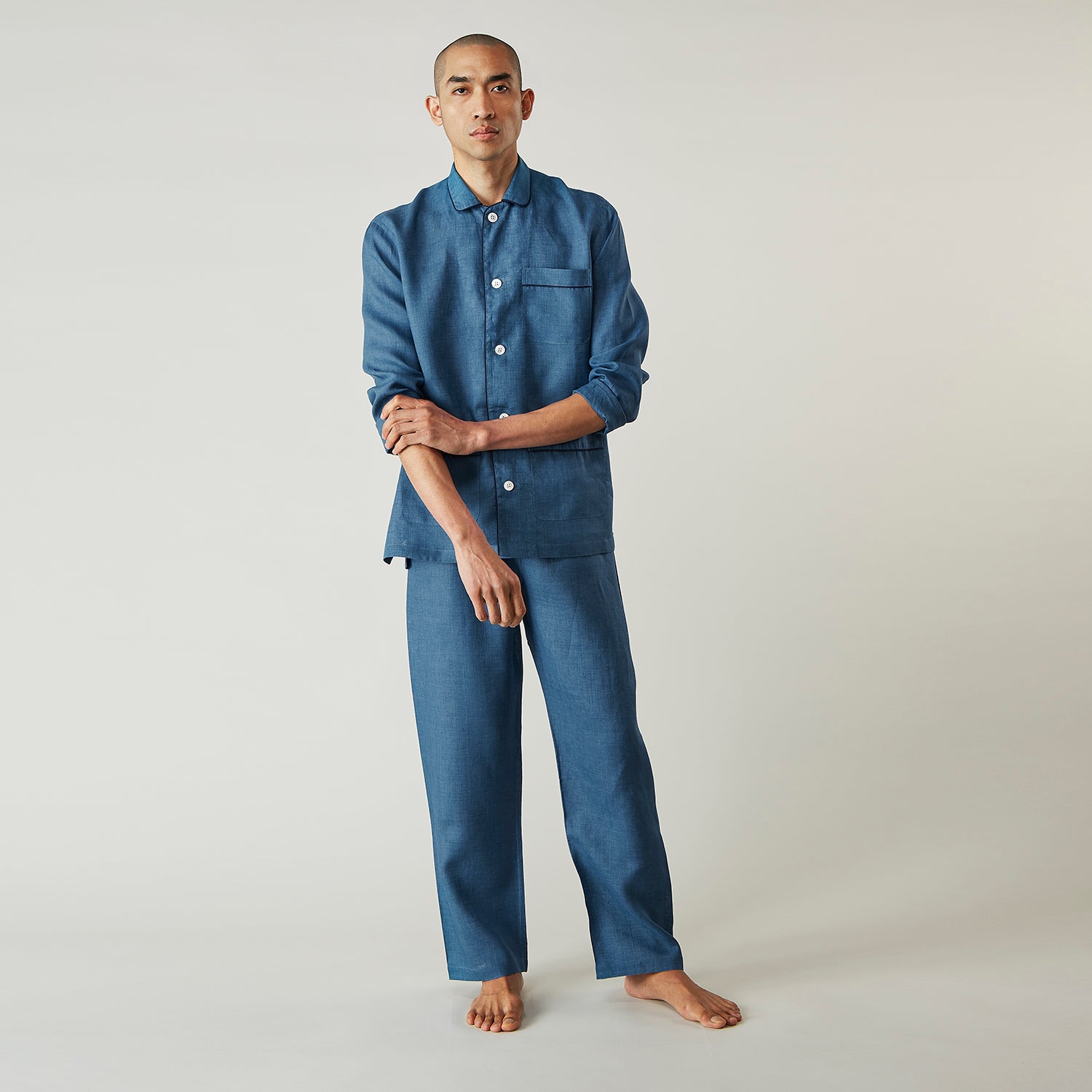 View 3 of product A person stands barefoot against a plain background, wearing the Teal Linen Modern Pyjama Set from Turnbull & Asser.