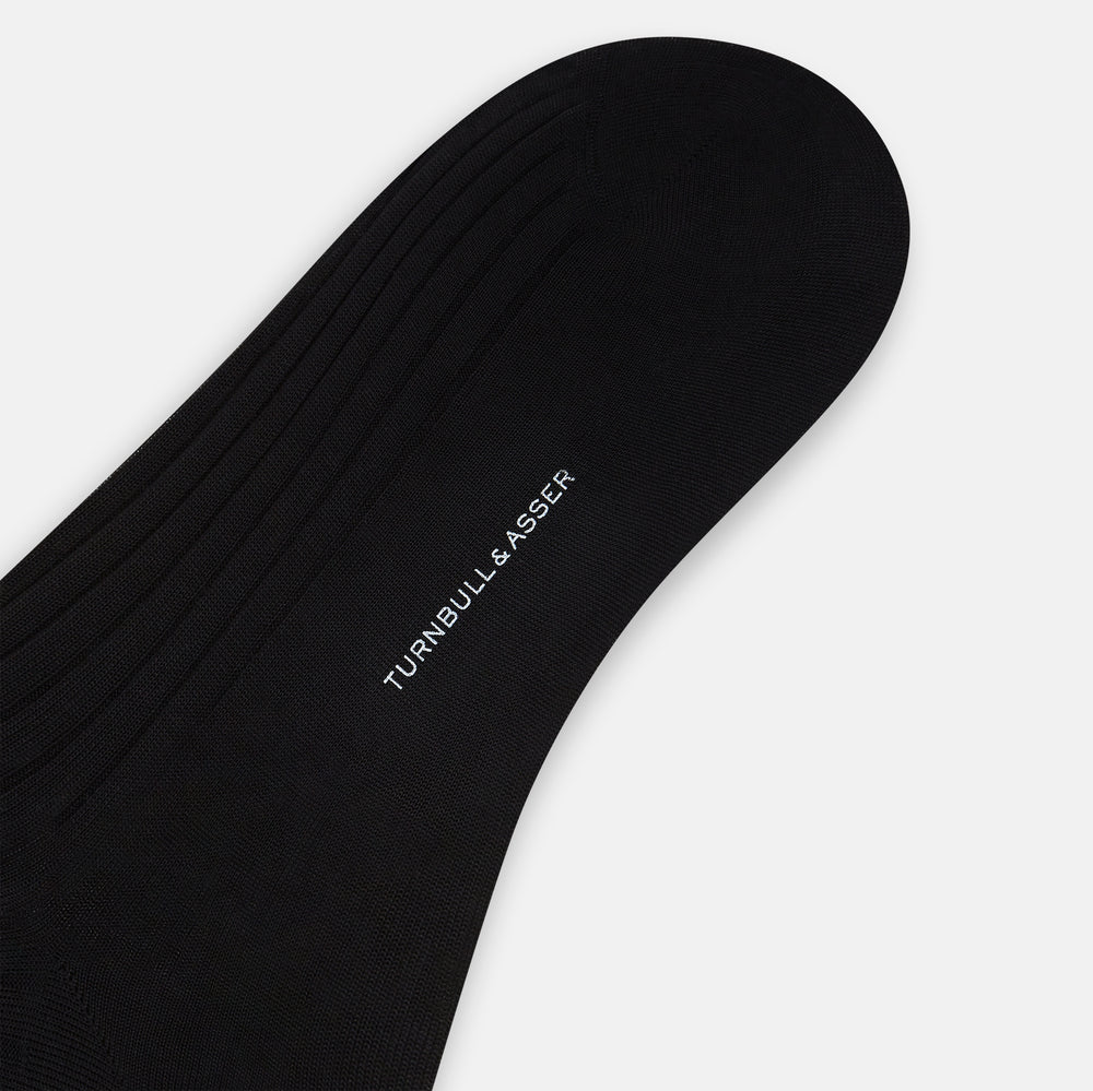 A single Turnbull & Asser Black Cotton Long Sock is shown upright on a white background, featuring a ribbed texture along the leg and foot with a smooth finish at the top.