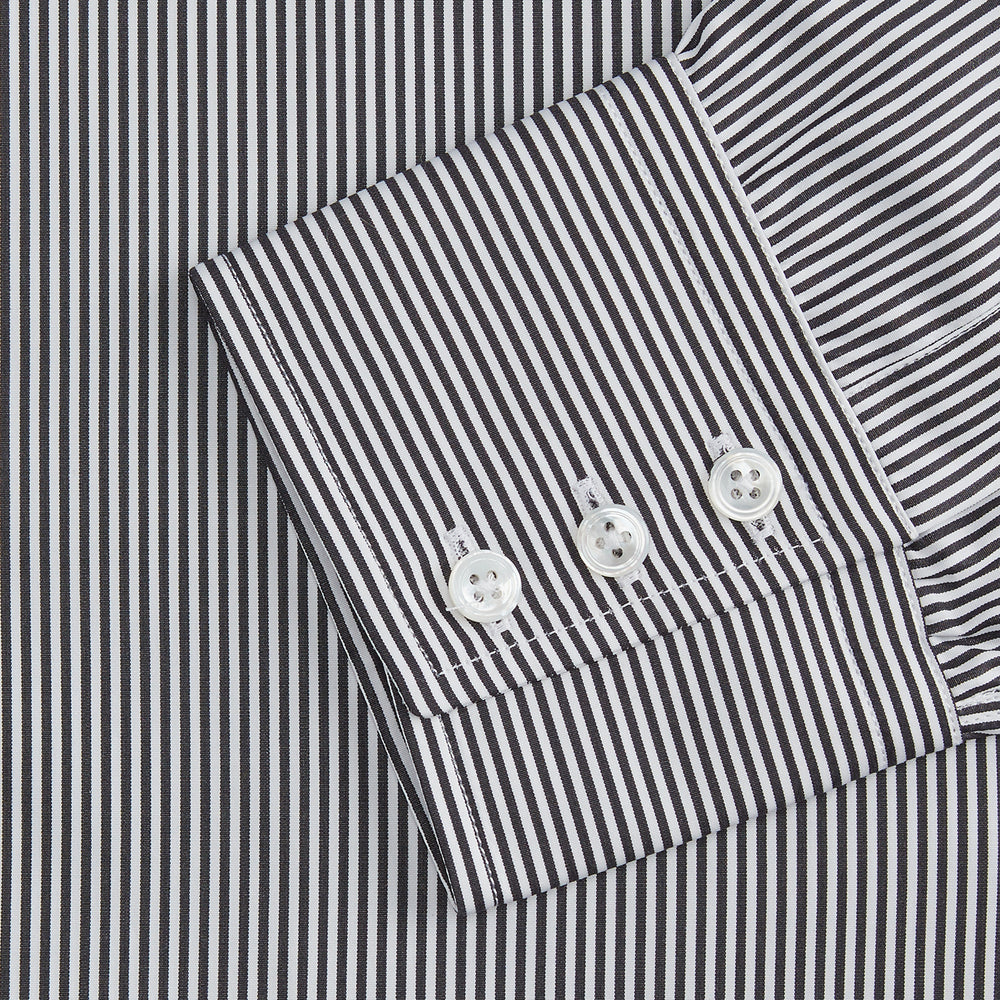 The Turnbull & Asser Black Candy Stripe Cotton Regular Fit Mayfair Shirt features long sleeves, a T&A collar, white buttons, and thin black stripes, displayed on a plain white background.