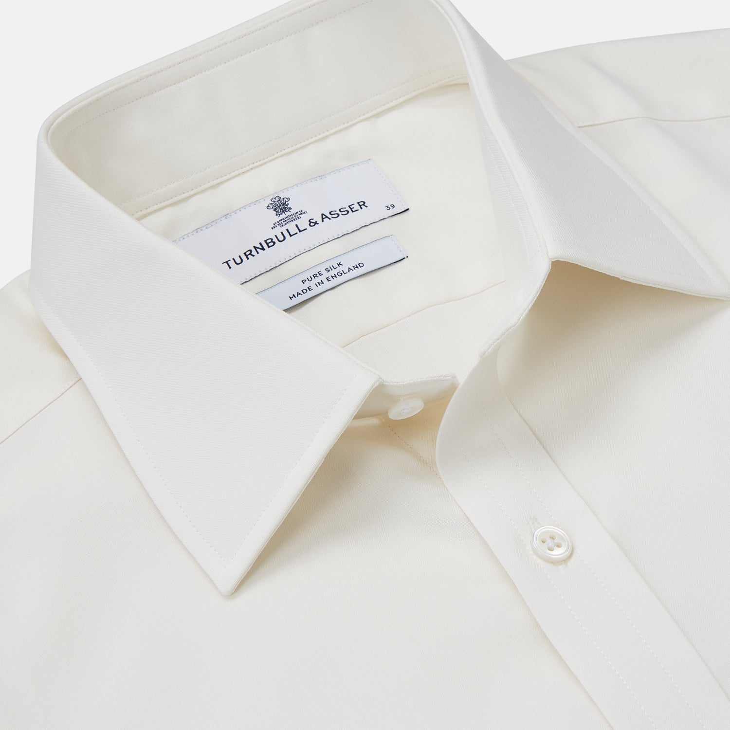 View 2 of product The Turnbull & Asser Cream Silk Tailored Fit Shirt is a long-sleeve button-up with a pointed collar and buttoned cuffs, displayed laid flat against a plain white background.