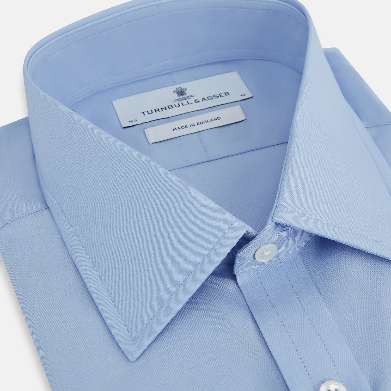 View 2 of product The Turnbull & Asser Blue Cotton Shirt features a T&A collar, double cuffs, and white buttons. This classic formal shirt is perfect for any gentleman and pairs effortlessly with a navy suit. Displayed on a plain white background.