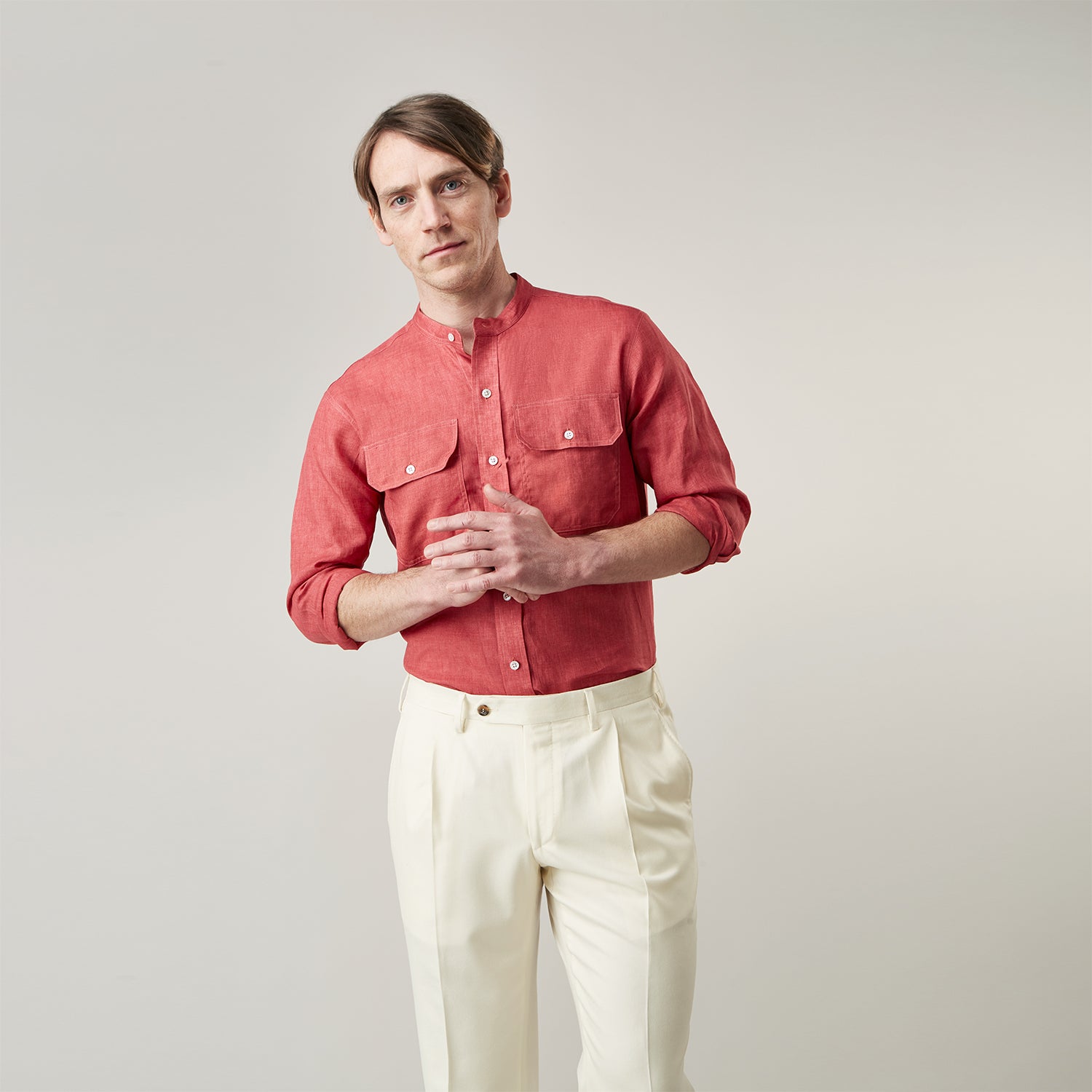 View 3 of product The Turnbull & Asser Plain Red Linen Weekend Fit Shirt with Stand Collar features long sleeves, a button-up front, and two buttoned-flap chest pockets. It is shown neatly laid flat on a plain light background.