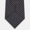 View 3 of product The Turnbull & Asser Navy and Orange Geometric Motif Silk Tie features a dark blue base with small orange, white, and light blue geometric patterns—a refined statement of British craftsmanship.