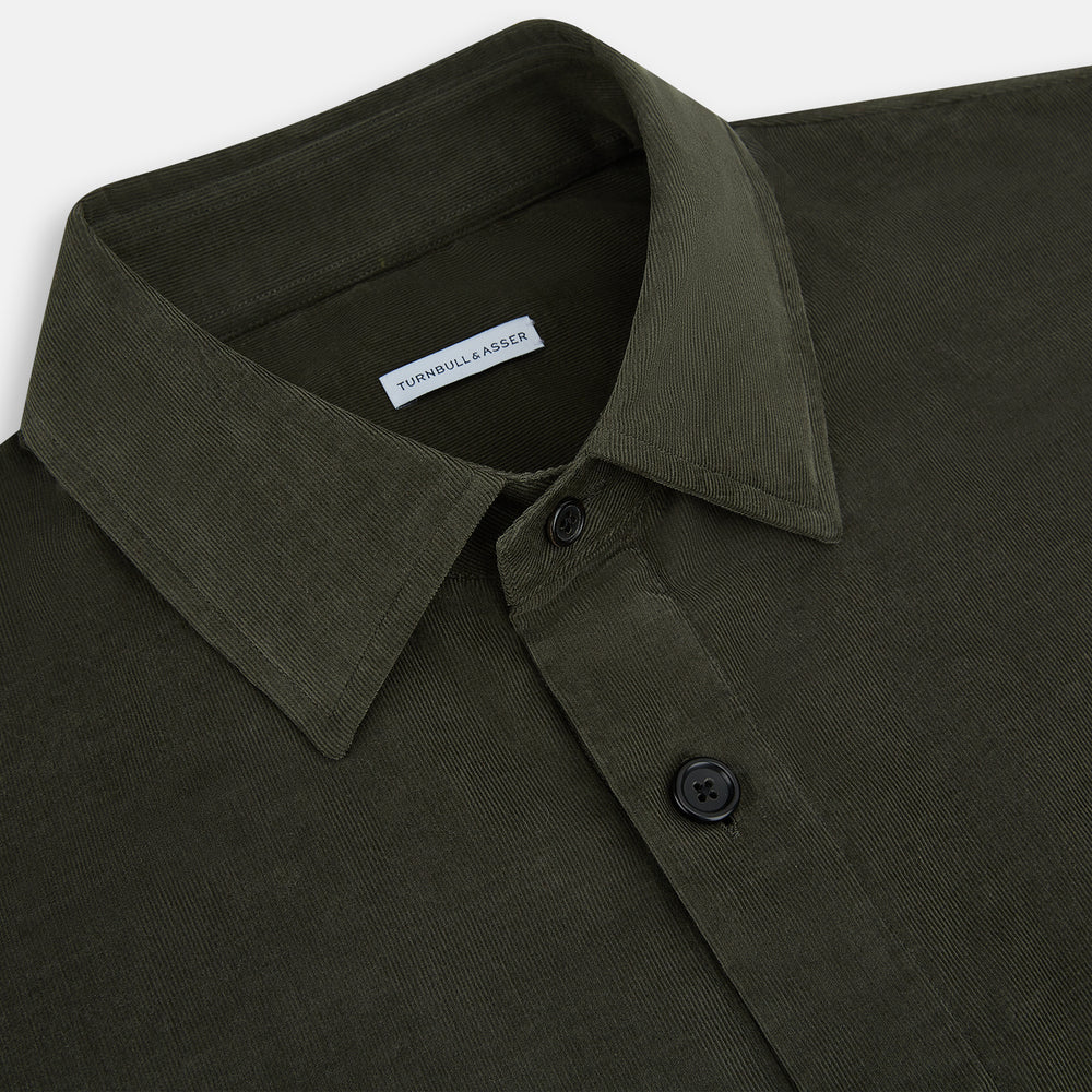 The Turnbull & Asser Olive Corduroy Hampstead Overshirt for men features a collar, long sleeves, left chest pocket, and two zippered side pockets, shown laid flat on a white background.