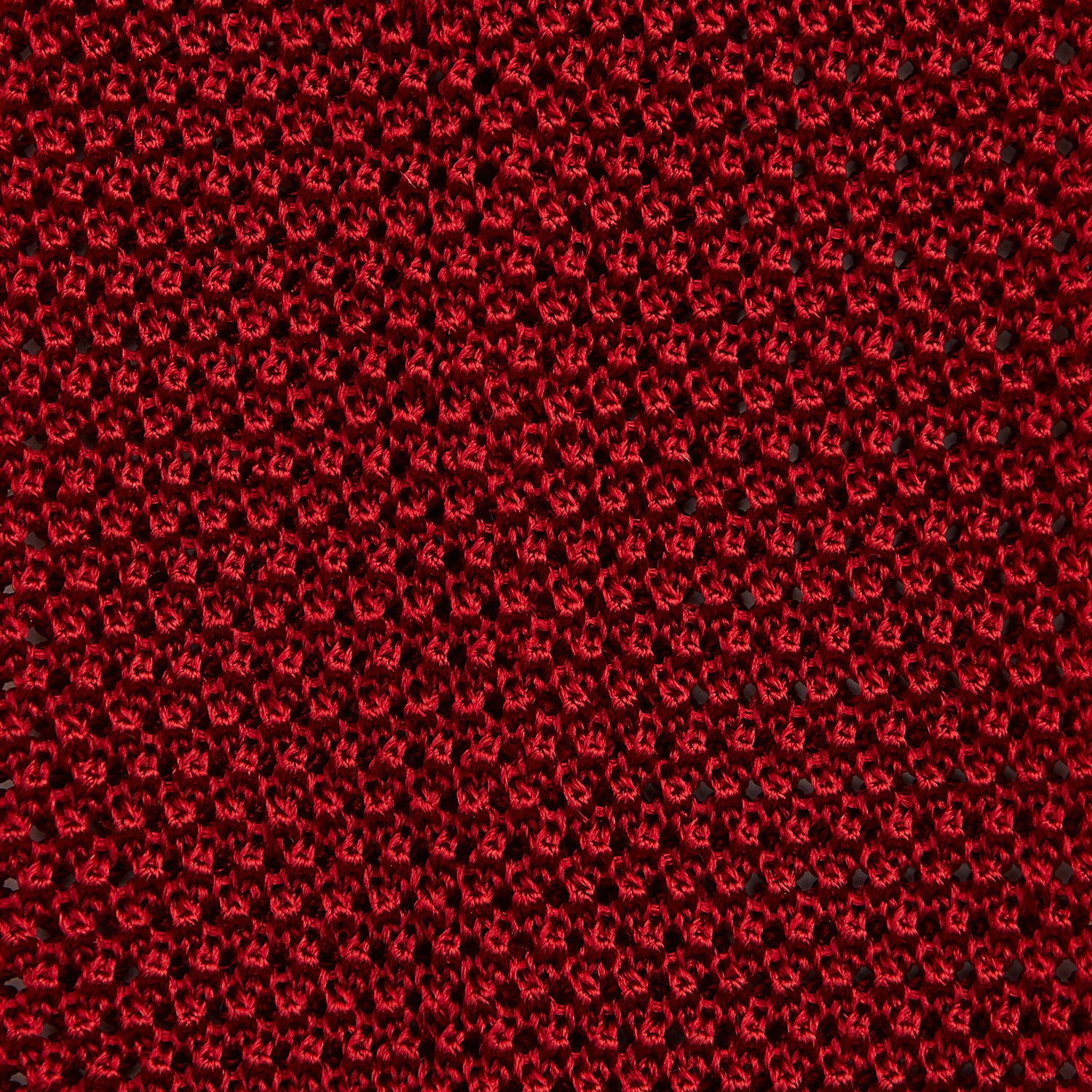 View 3 of product The Turnbull & Asser KNITTED RED SILK PLAIN TIE, featuring a textured finish, is rolled up and displayed against a plain white background.