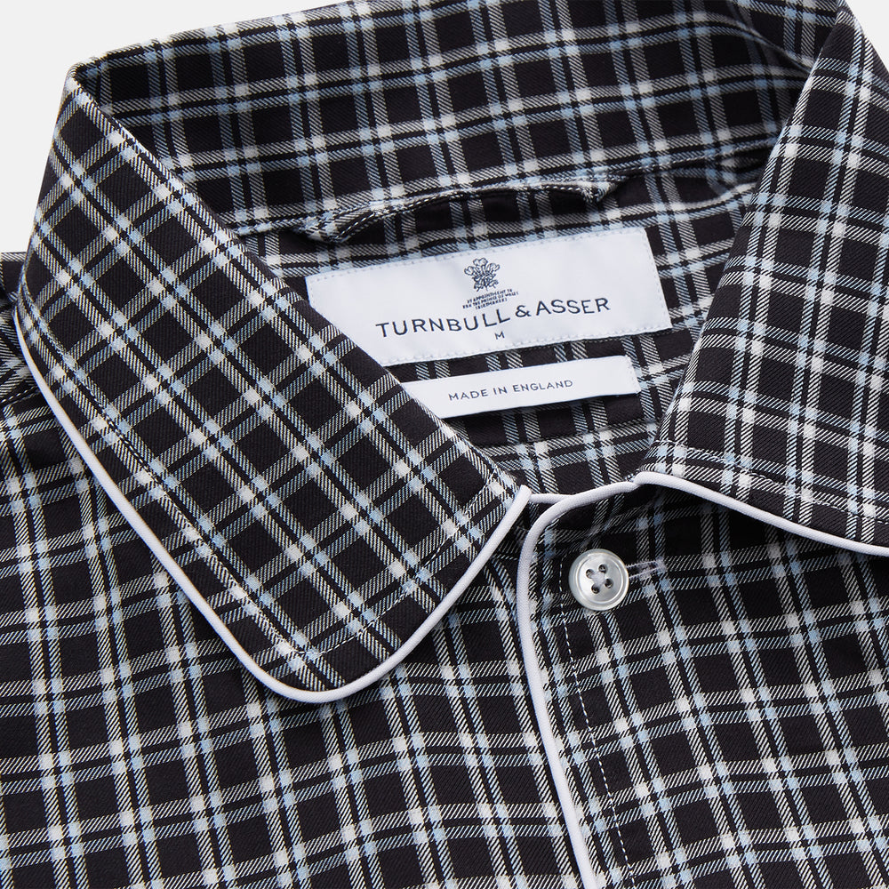 The Turnbull & Asser Black Multi Check Cotton Blend Sussex Nightshirt features a long sleeve, knee-length design with front buttons, a pointed collar, and chest pocket—ideal for those who love luxury sleepwear.