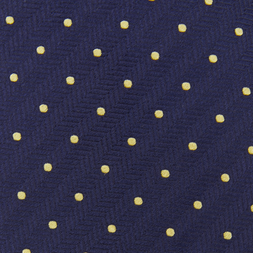 The Turnbull & Asser Navy Spot Woven Herringbone Silk Tie features a navy blue base with evenly spaced yellow polka dots, making it an essential accessory for smart attire. Displayed rolled on a white background.