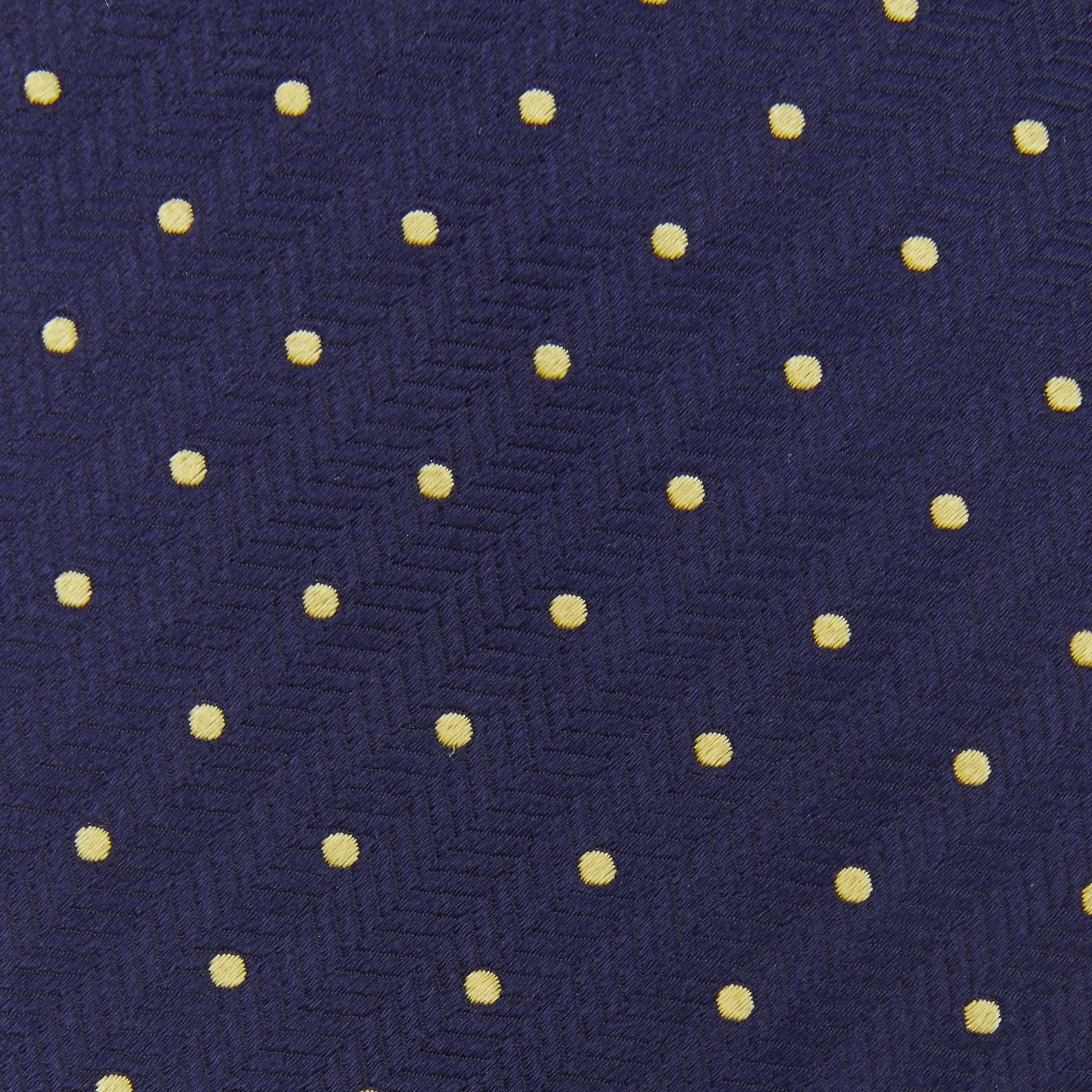 View 4 of product The Turnbull & Asser Navy Spot Woven Herringbone Silk Tie features a navy blue base with evenly spaced yellow polka dots, making it an essential accessory for smart attire. Displayed rolled on a white background.