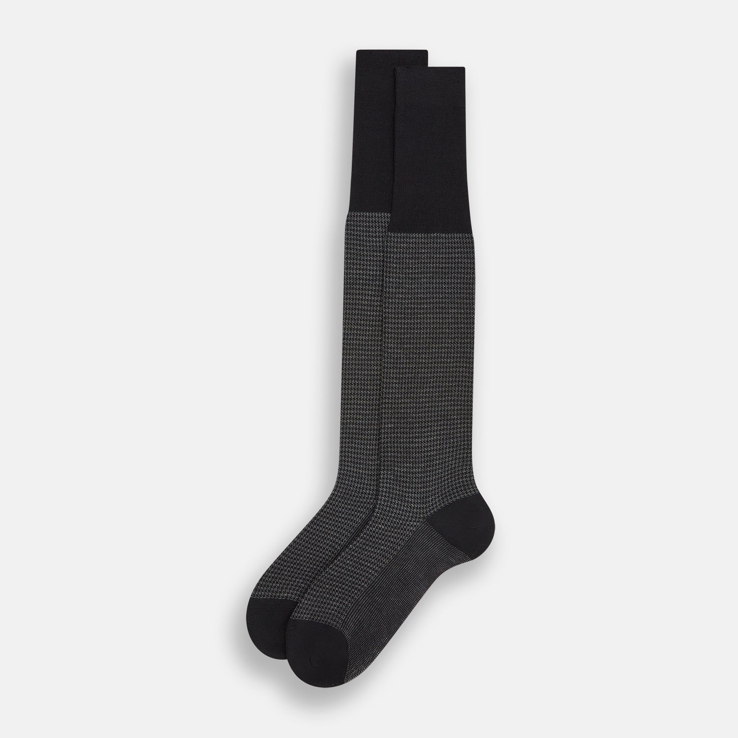 View 2 of product The Turnbull & Asser Charcoal Melange Houndstooth Long Sock is knee-high, with a subtle dark houndstooth pattern and solid black toe, heel, and cuff, shown on a white background.