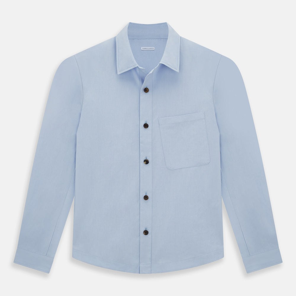 The Turnbull & Asser Pale Blue Hyde Overshirt is a long-sleeve, sanforised cotton button-up with a single chest pocket and dark buttons, shown on a plain white background.