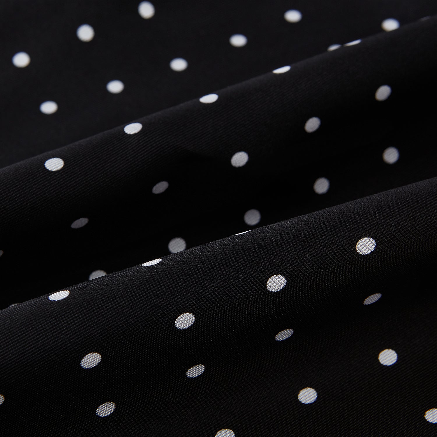 View 3 of product The Black and White Spotted Silk Scarf by Turnbull & Asser features a spotted design, neatly folded at the top and spread out at the bottom, with the brand's name printed in white near its fringed ends.