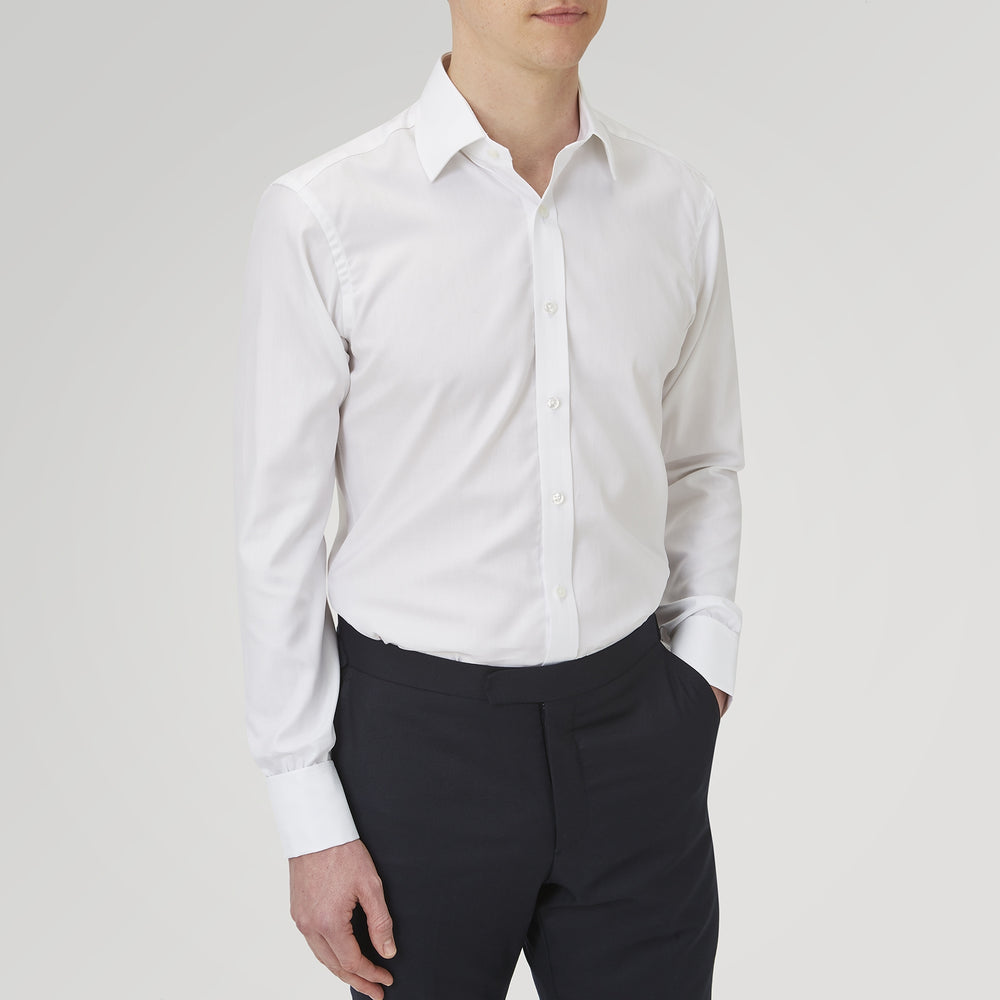 The Turnbull & Asser White Herringbone Sea Island Quality Cotton Shirt features a T&A collar, double cuffs, and chest pocket. Crafted for luxury with a classic design, it’s shown neatly folded against a light grey background—ideal for evening wear.