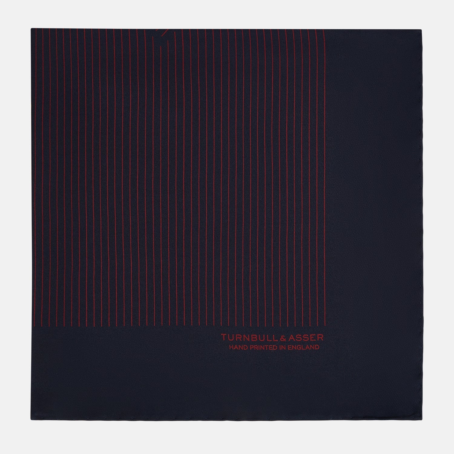 View 3 of product The Turnbull & Asser Navy and Burgundy Stripe Silk Pocket Square features diagonal stripes in one corner, hand-rolled edges, and "TURNBULL & ASSER HAND PRINTED IN ENGLAND" printed in red on luxurious silk.